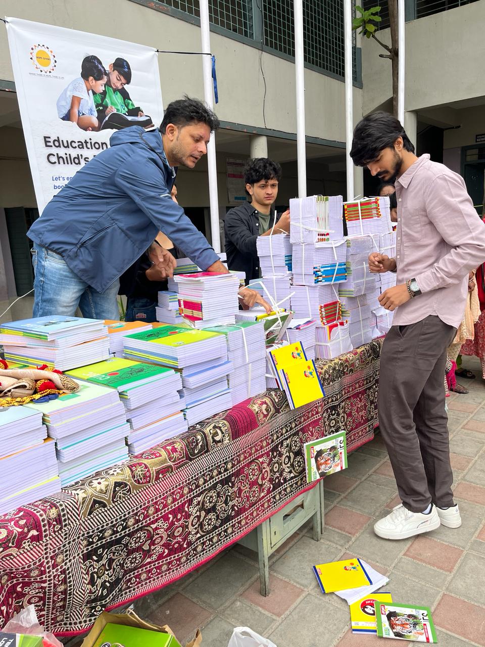 Distribution of notebook stacks to students at an educational drive