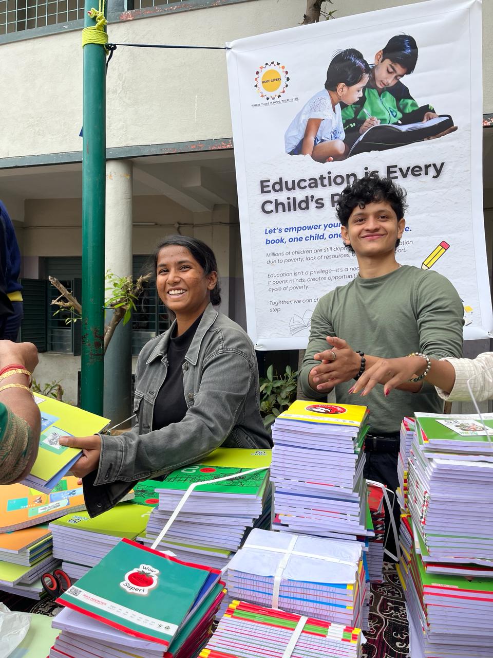 Volunteers distributing stacks of notebooks for underprivileged students.