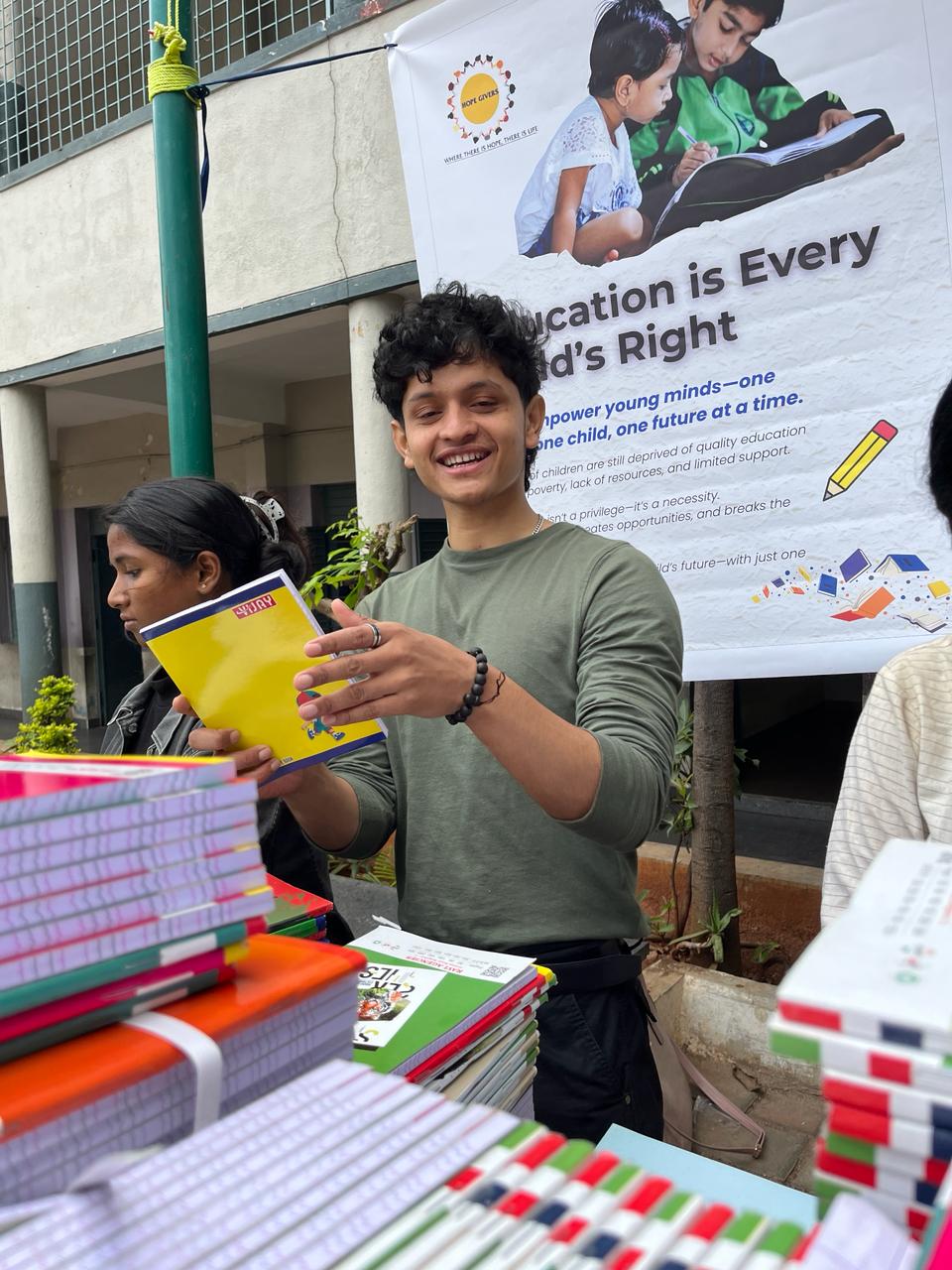 Smiling young man distributing notebooks at an educational event