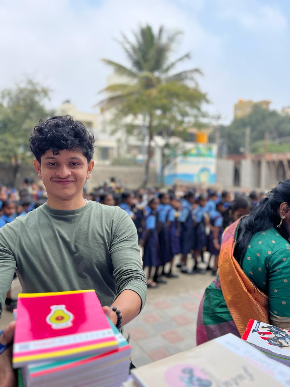 A volunteer distributing books to students at a school.