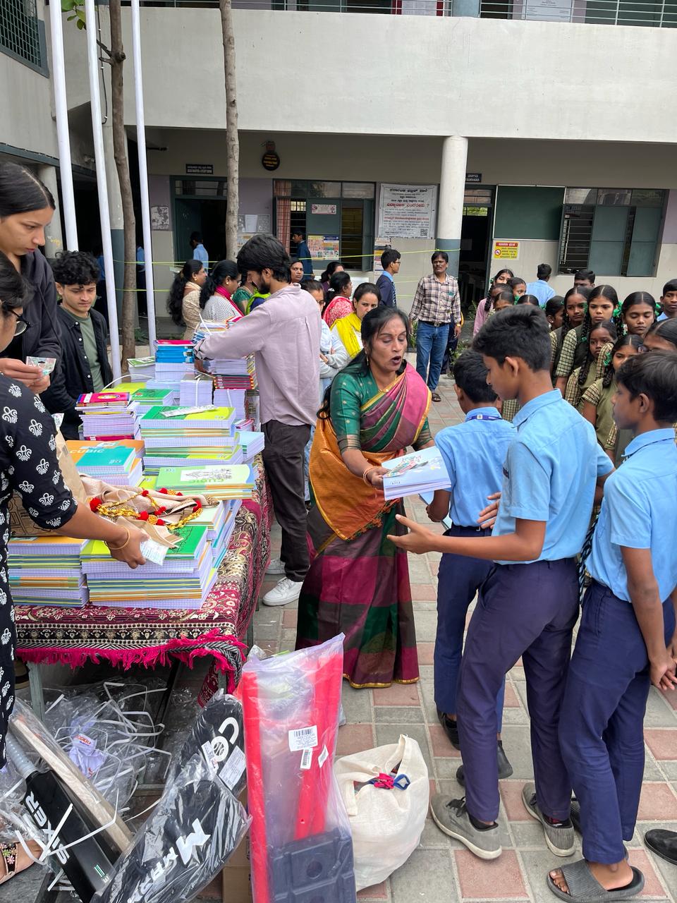 Staff distributing notebooks to school children during an educational event.