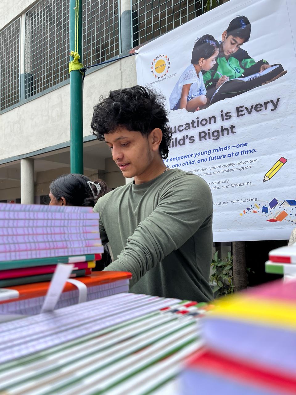 A volunteer arranging notebooks for an NGO educational drive.