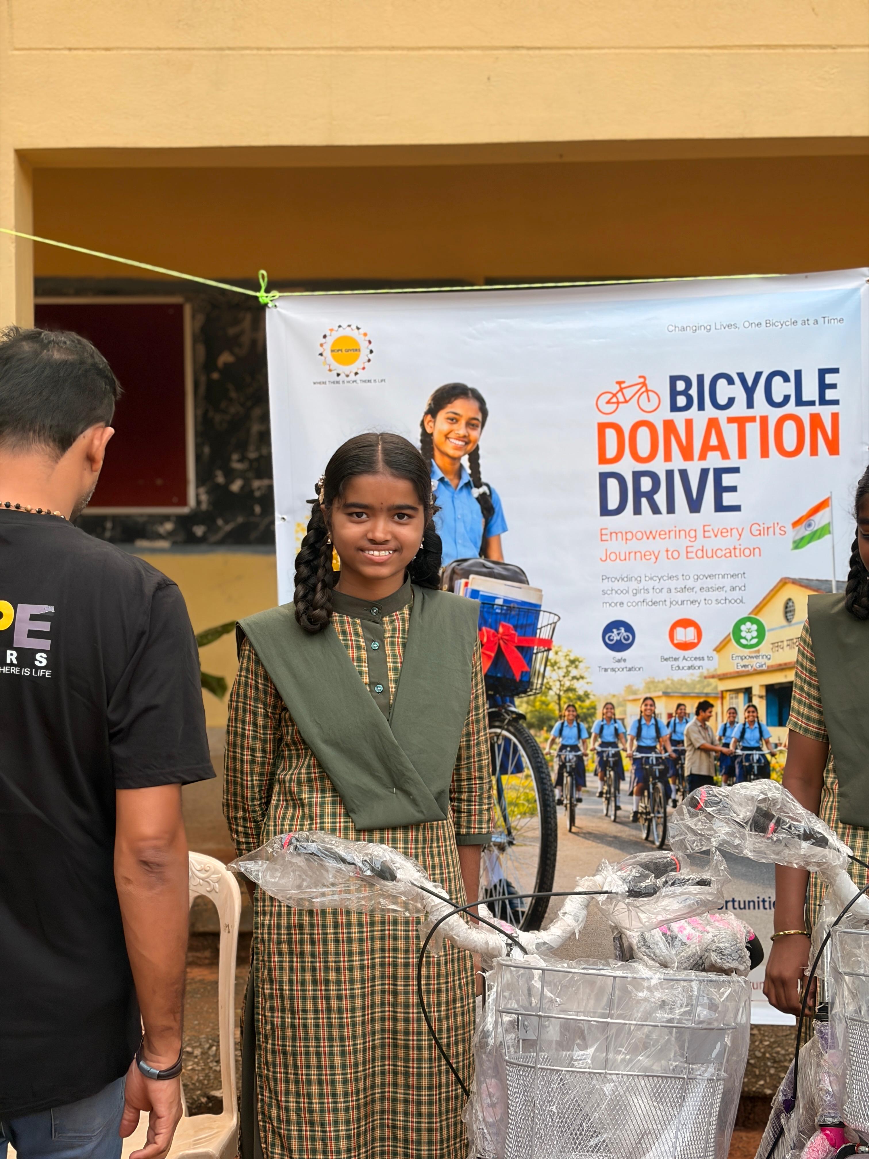 A student smiles beside her bicycle at the donation drive